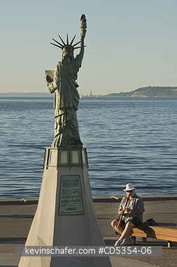 SEATTLE: Man playing flute below miniature Statue of Liberty Alki Beach, Seattle, Washington SUMMER