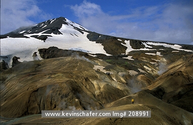 ICELAND: Iceland, Interior Highlands, Kerlingarfioll, Stream dissects Hyeradalir Thermal area, Man hiking in the landscape.